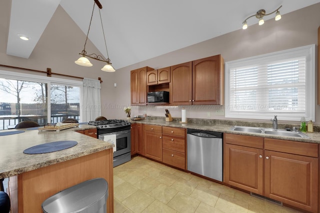 kitchen with decorative light fixtures, vaulted ceiling, kitchen peninsula, sink, and appliances with stainless steel finishes