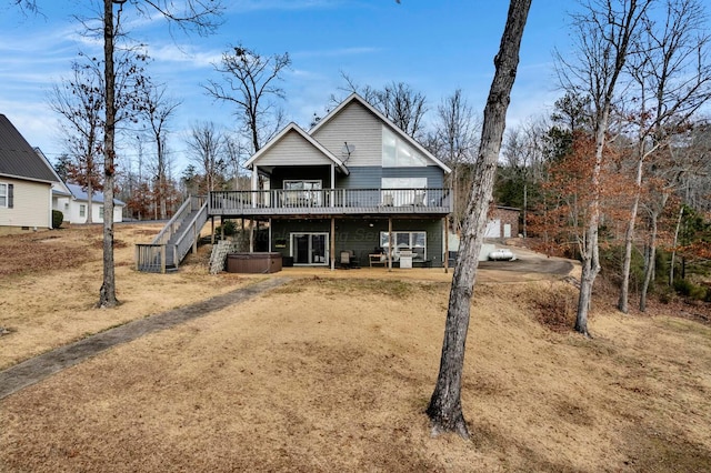 rear view of property featuring a hot tub and a wooden deck