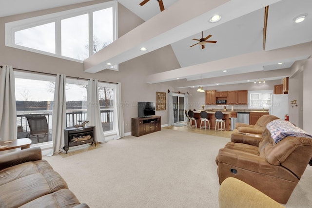 living room featuring ceiling fan, light colored carpet, and a towering ceiling