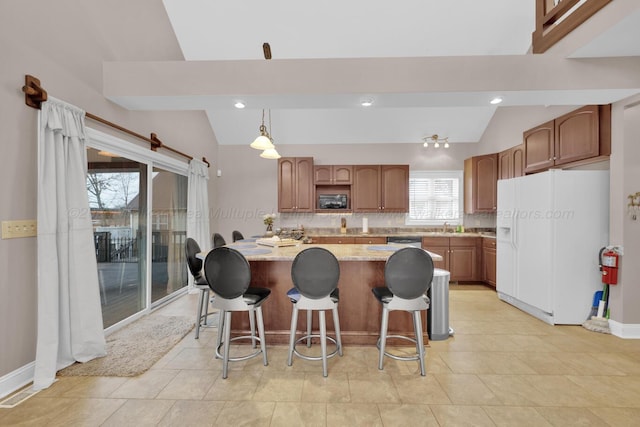 kitchen with vaulted ceiling, backsplash, black microwave, white fridge with ice dispenser, and light stone counters