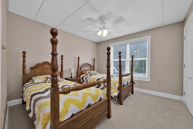 carpeted bedroom with ceiling fan and a drop ceiling