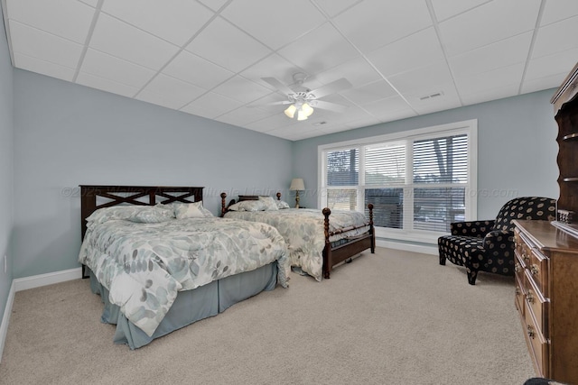 carpeted bedroom with ceiling fan and a drop ceiling