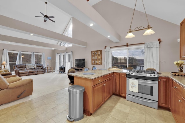 kitchen featuring kitchen peninsula, hanging light fixtures, light carpet, stainless steel gas stove, and light stone counters