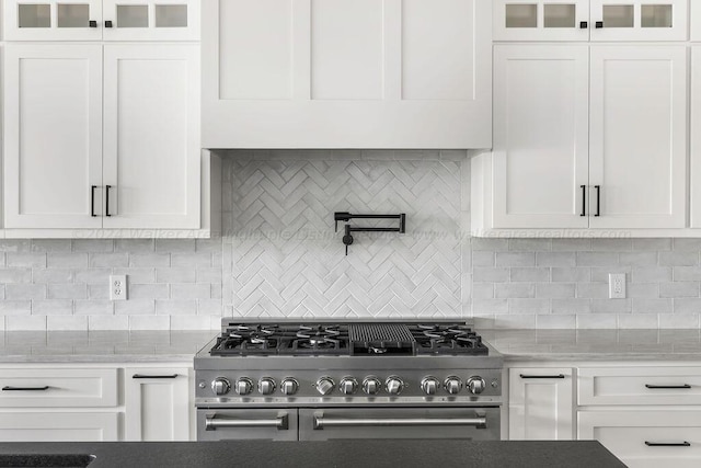 kitchen with backsplash, stainless steel range, and white cabinets