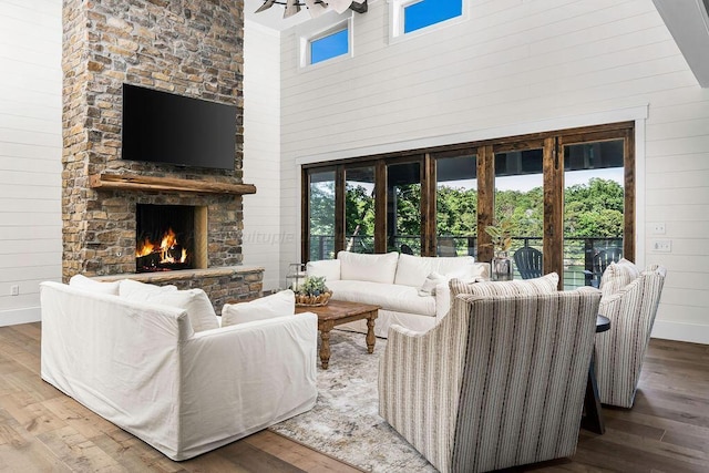 living room featuring french doors, a high ceiling, wood walls, hardwood / wood-style floors, and a fireplace