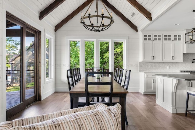 dining room featuring vaulted ceiling with beams, wood walls, and hardwood / wood-style flooring