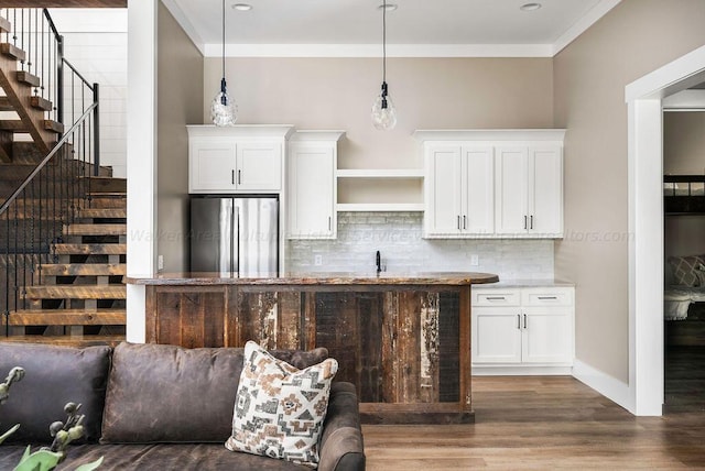 bar with decorative backsplash, stainless steel fridge, wood-type flooring, decorative light fixtures, and white cabinets