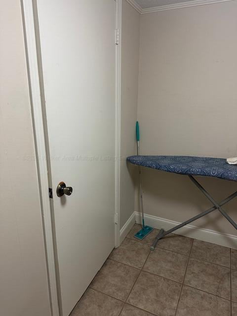 clothes washing area featuring light tile patterned floors, baseboards, and ornamental molding