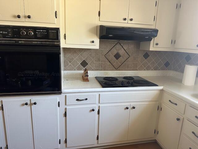 kitchen with under cabinet range hood, white cabinetry, black appliances, and light countertops