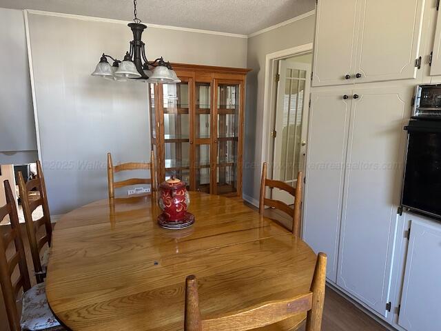 dining space featuring french doors, a textured ceiling, an inviting chandelier, and ornamental molding