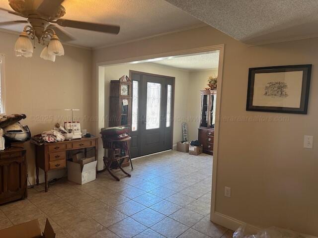 tiled entryway with a textured ceiling, ceiling fan, and crown molding