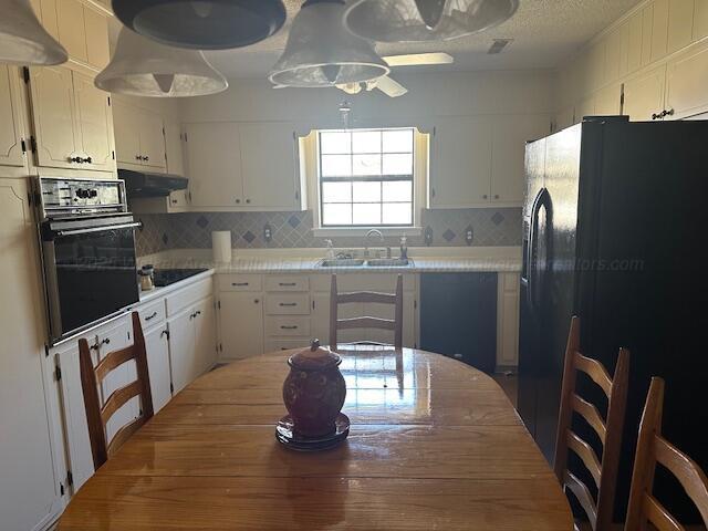 kitchen with black appliances, white cabinets, under cabinet range hood, and a sink