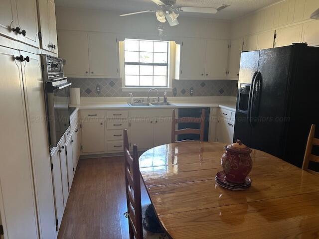 kitchen featuring black appliances, a sink, tasteful backsplash, white cabinets, and ceiling fan