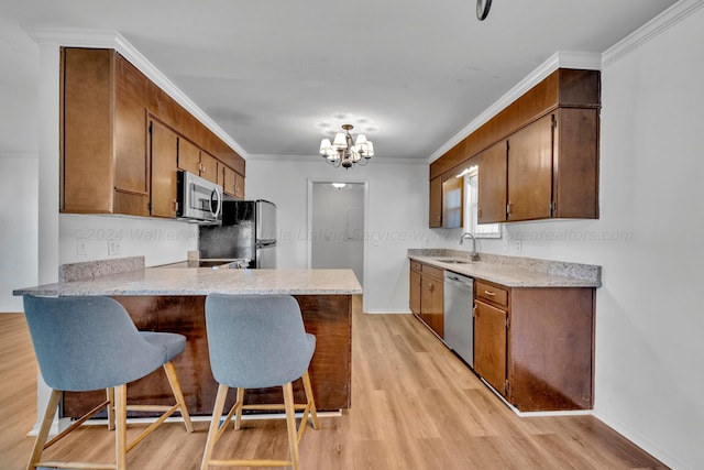 kitchen featuring light hardwood / wood-style flooring, a kitchen bar, kitchen peninsula, stainless steel appliances, and a chandelier