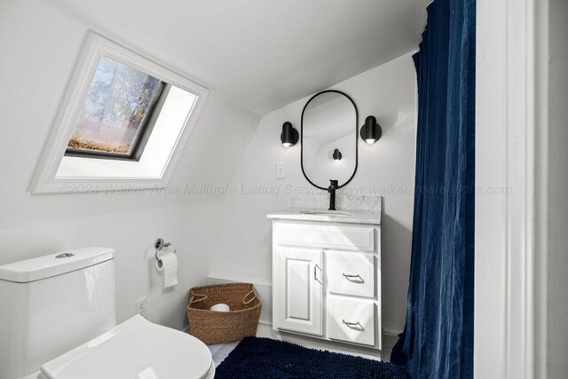 bathroom with vanity, toilet, and lofted ceiling with skylight