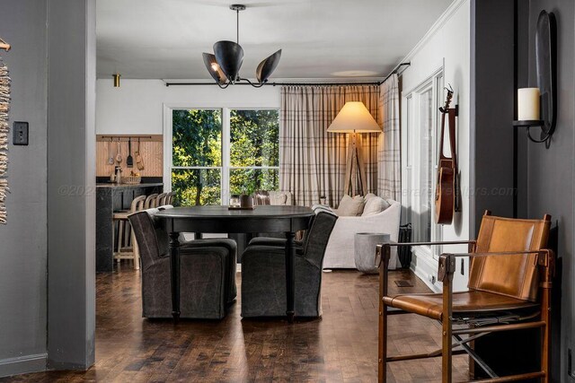 dining area featuring a chandelier, dark wood-type flooring, and ornamental molding