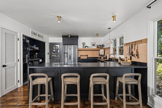 kitchen with stainless steel fridge, dark hardwood / wood-style flooring, stacked washer and dryer, and a wealth of natural light