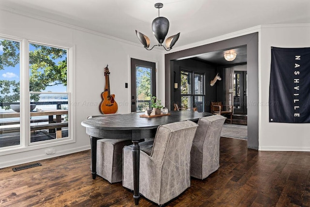 dining space with dark hardwood / wood-style floors, crown molding, and a chandelier