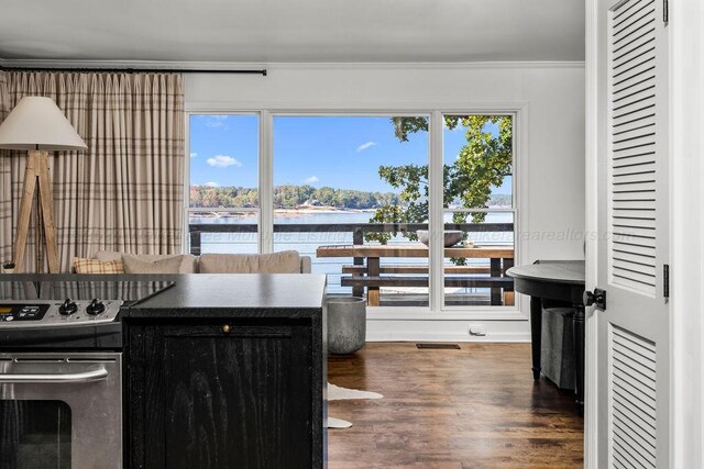 kitchen with electric range, dark hardwood / wood-style floors, a water view, and crown molding