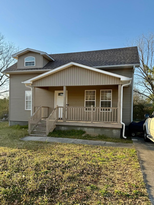 bungalow featuring a porch, a front yard, and a shingled roof