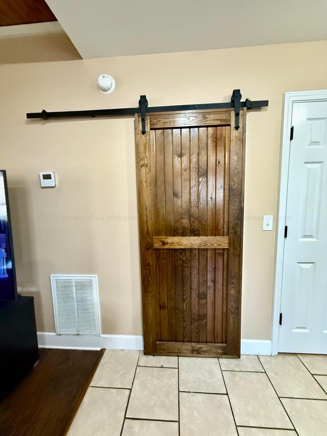 interior space featuring a barn door, baseboards, and visible vents