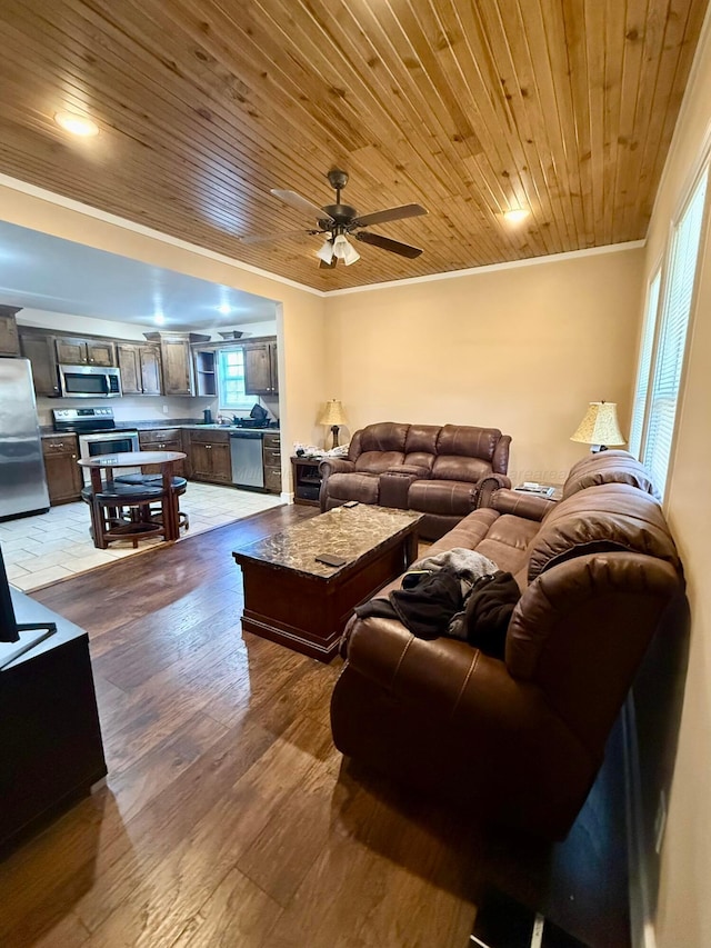 living area with wood ceiling, crown molding, a ceiling fan, and wood finished floors