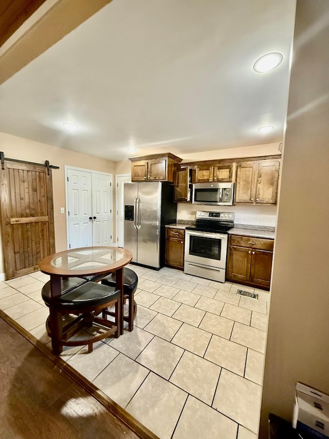 kitchen with visible vents, light countertops, a barn door, light tile patterned floors, and stainless steel appliances