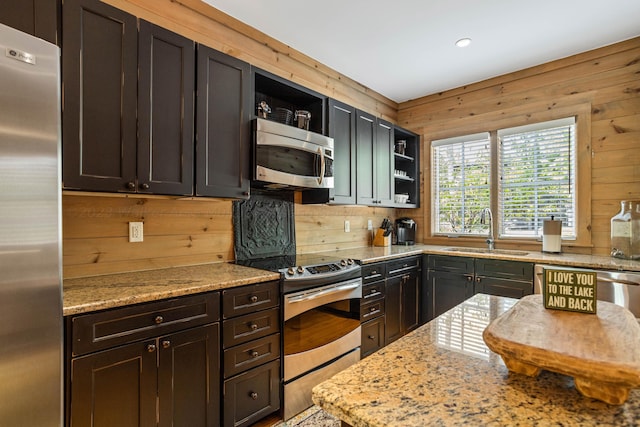 kitchen with stainless steel appliances, wooden walls, and sink