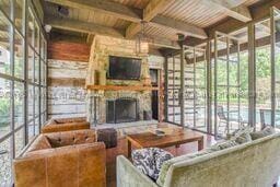 living room with a fireplace, beam ceiling, and wood ceiling