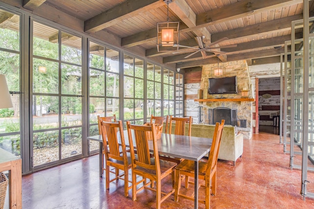 dining area featuring a stone fireplace, wooden ceiling, and beamed ceiling