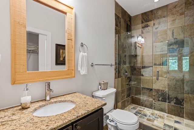 bathroom with toilet, a shower with door, and vanity