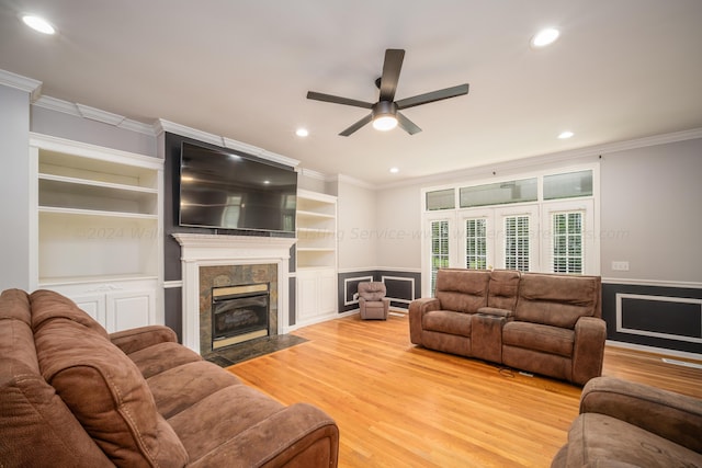 living room with a tile fireplace, ceiling fan, light hardwood / wood-style flooring, and ornamental molding