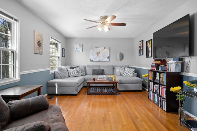 living room with ceiling fan, a textured ceiling, and light hardwood / wood-style flooring