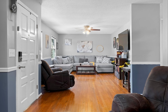 living room featuring hardwood / wood-style floors, a textured ceiling, and ceiling fan