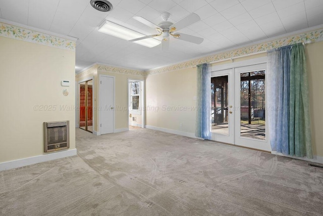 empty room featuring light carpet, french doors, crown molding, ceiling fan, and heating unit