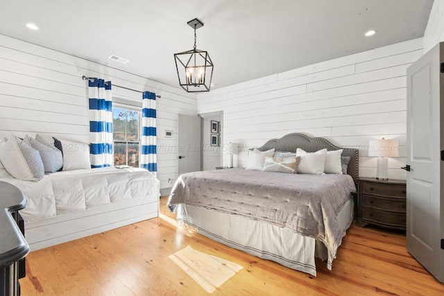 bedroom with wood walls, a chandelier, and hardwood / wood-style floors