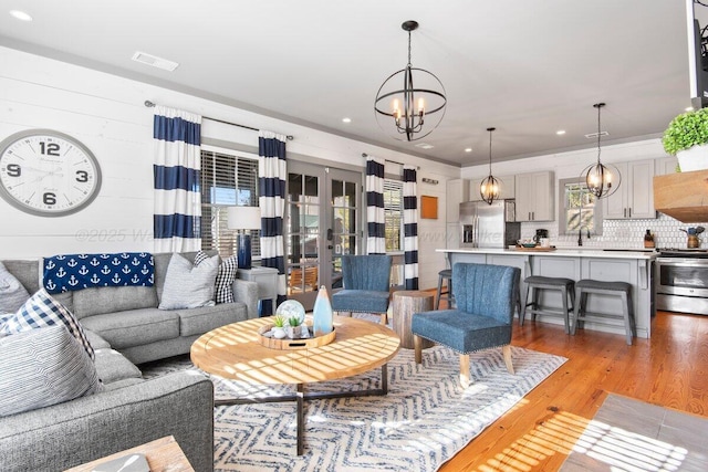 living room featuring sink, an inviting chandelier, and light hardwood / wood-style flooring