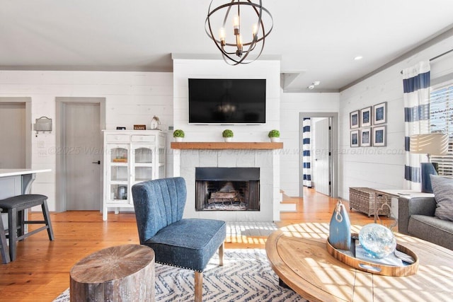 living room with an inviting chandelier, wood walls, and light hardwood / wood-style flooring