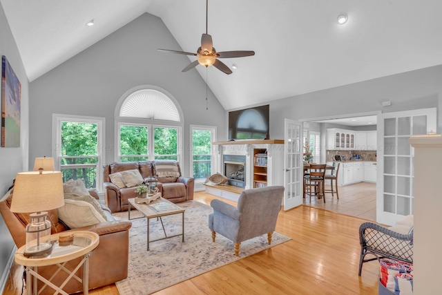 living room with ceiling fan, plenty of natural light, light hardwood / wood-style floors, and high vaulted ceiling