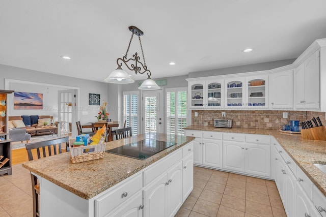 kitchen with decorative backsplash, black electric stovetop, pendant lighting, a center island, and white cabinetry