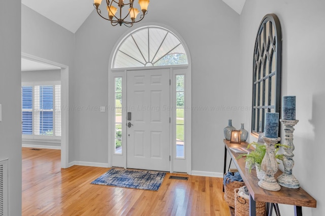 foyer with plenty of natural light, wood-type flooring, and lofted ceiling