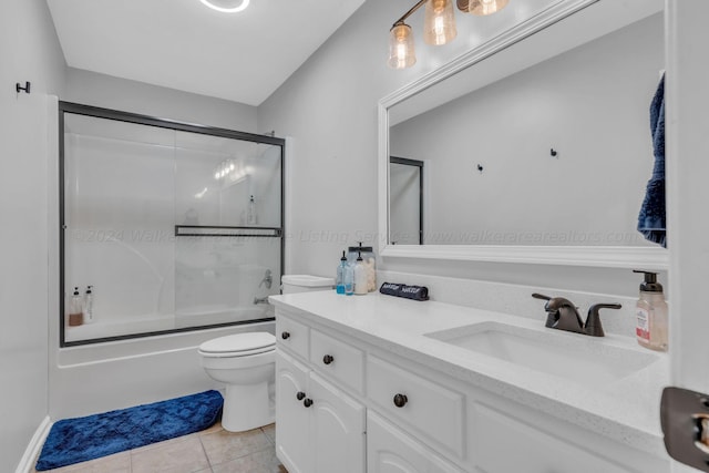 full bathroom featuring combined bath / shower with glass door, vanity, tile patterned flooring, and toilet