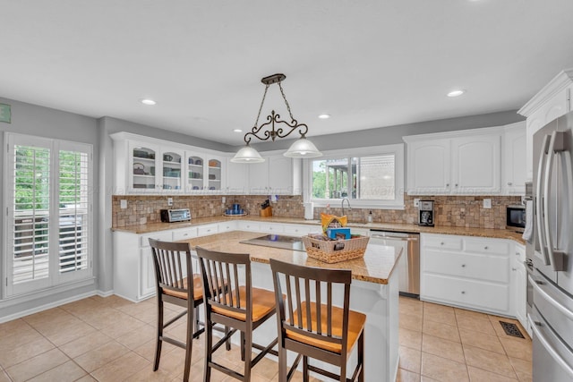 kitchen featuring backsplash, white cabinets, a kitchen island, and appliances with stainless steel finishes