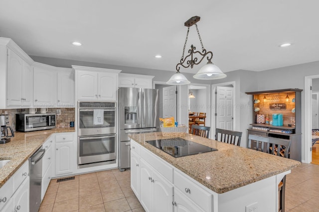 kitchen with white cabinets, a center island, stainless steel appliances, and hanging light fixtures