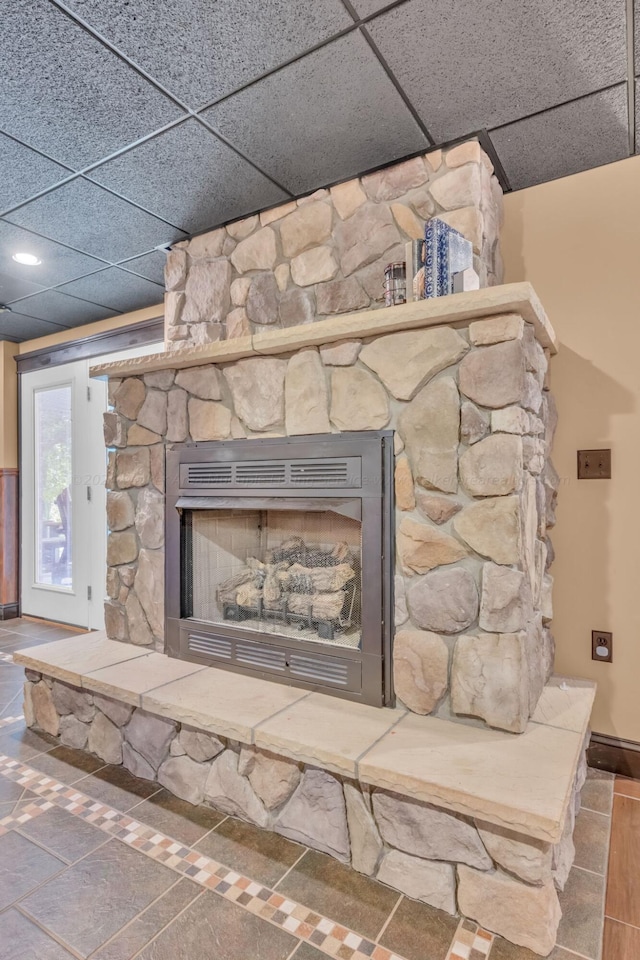 details with a drop ceiling and a stone fireplace