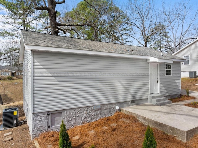 exterior space featuring crawl space, a patio area, central air condition unit, and a shingled roof