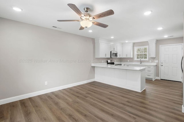 kitchen featuring appliances with stainless steel finishes, a peninsula, light countertops, white cabinetry, and visible vents