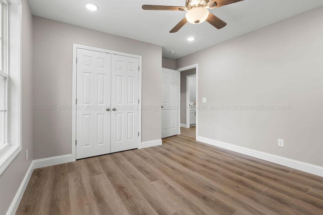 unfurnished bedroom with a closet, recessed lighting, light wood-style floors, and baseboards