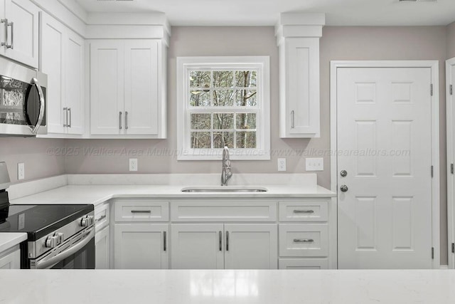 kitchen with stainless steel appliances, a sink, and white cabinets