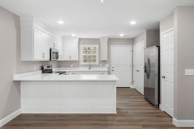 kitchen with stainless steel appliances, a peninsula, white cabinets, light countertops, and a sink